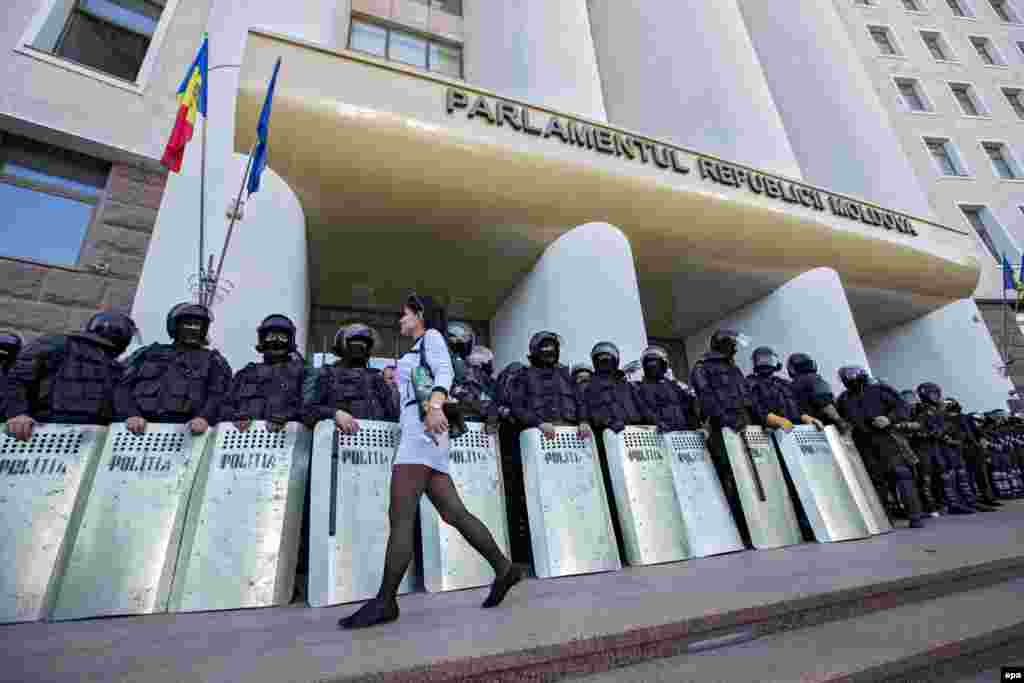 A woman walks past riot police guarding the parliament building during a protest against Moldova&#39;s government in the capital, Chisinau on October 4. (epa/Dumitru Doru)