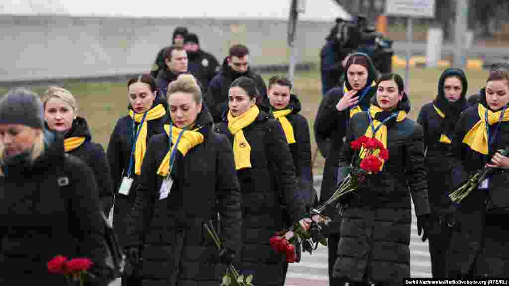 Colleagues of the crew members of Ukraine International Airlines arrive for the ceremony on the tarmac.