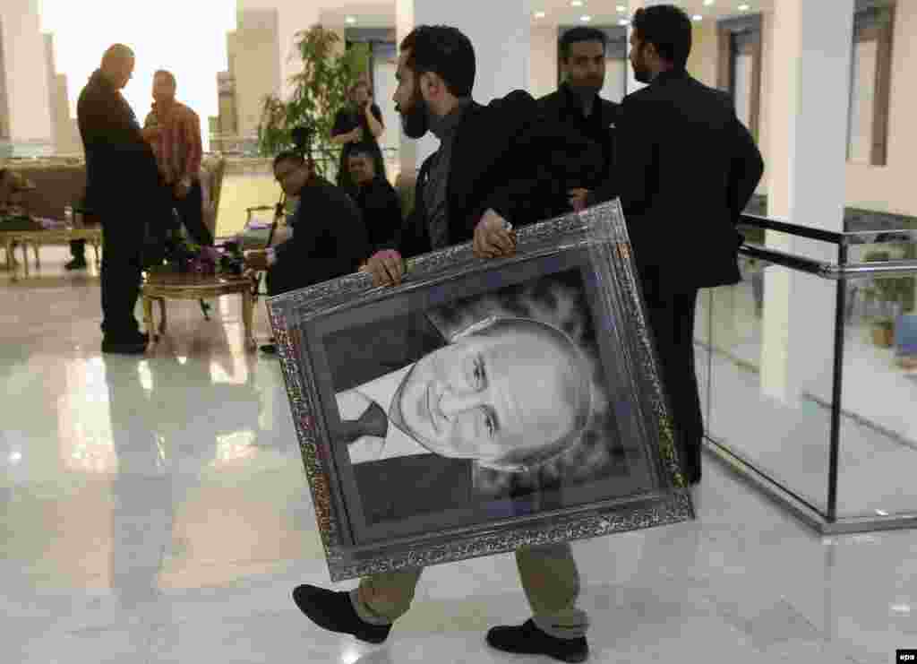 An unidentified Iranian man caries a portrait of Russian President Vladimir Putin in a congress center hosting the Gas Exporting Countries Forum summit in Tehran. (epa/Sergei Chirikov)