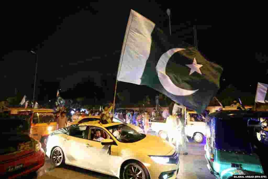A large Pakistani flag is waved from a car in Peshawar.