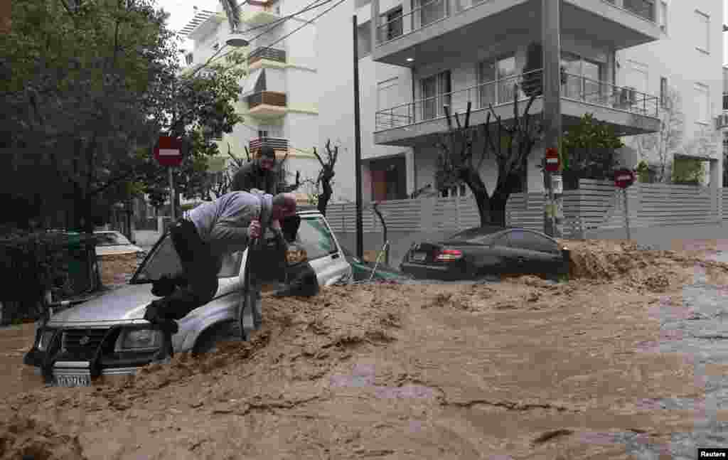 O femeie este salvată din mașina sa prinsă de o viitură &icirc;n suburbia Chalandri, Atena, Grecia, 22 februarie 2013.