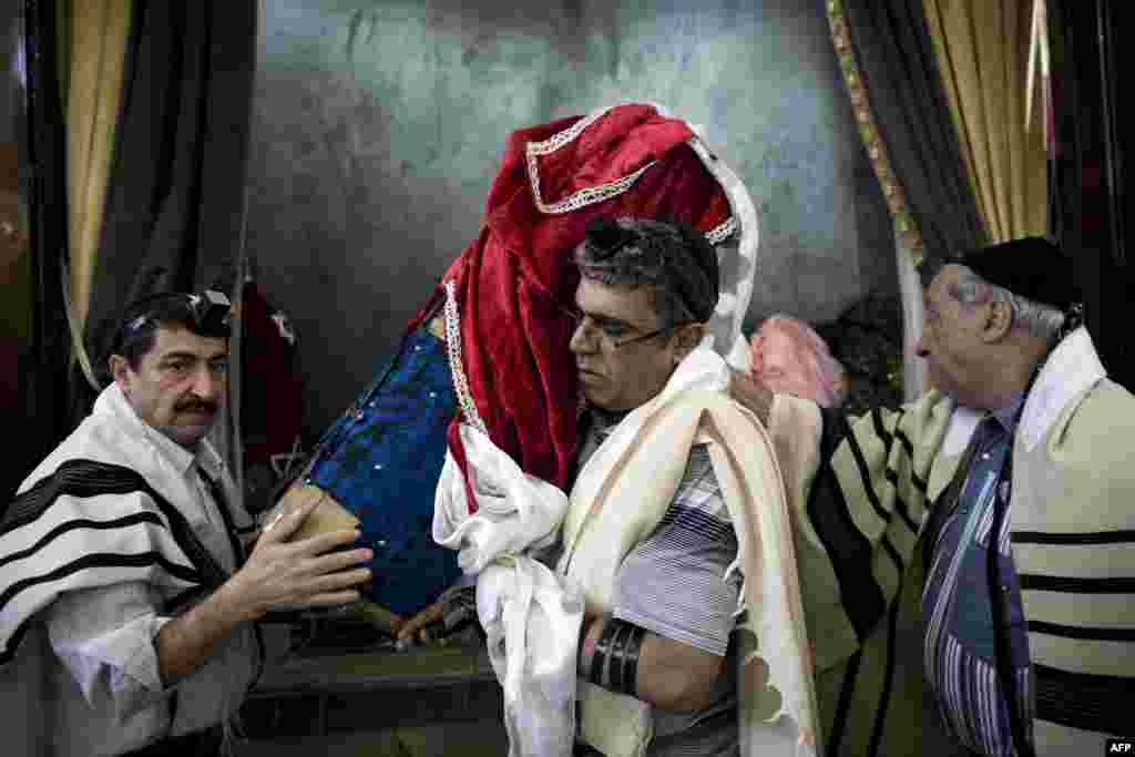 Iranian Jews carry a Torah scroll out from a cupboard to be read during morning prayers.