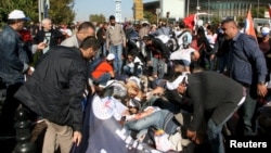 Wounded people on the ground as survivors offer help after an explosion during a peace march in Ankara, Turkey.