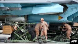 Российские военные закрепляют бомбы на военном самолете Су-34 на авиабазе Хмеймим в Сирии. 4 мая 2016 года.