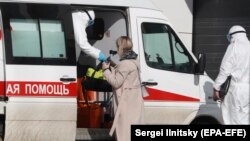 Medical workers wearing protective clothing take a suspected COVID-19 patient into quarantine. One Russian NGO says it's been contacted by many people in quarantine who feel abandoned without information.