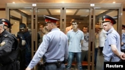 Defendants facing trial over clashes with the police during the Bolotnaya protests stand inside a glass-walled cage before a court hearing in Moscow on June 6.