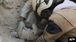 Trupul unui copil scos din ruinele unei clădiri după bombardamentele asupra orașului Alep