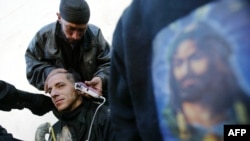 A Shi'ite Muslim has his head shaved alongside a picture of Imam Hussein on the eve of Ashura.