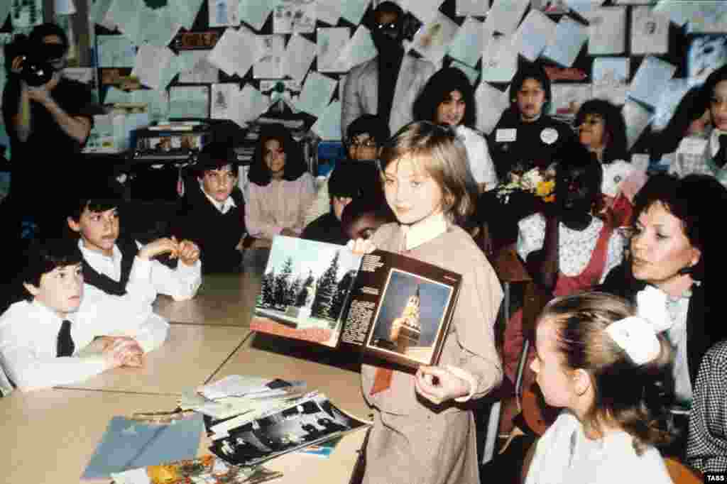 Lycheva shows pictures of Russian landmarks to American schoolkids. Her U.S. tour followed the highly publicized visit of American schoolgirl Samantha Smith to the Soviet Union in 1983. Smith died in a plane crash in 1985, and Lycheva disappeared from public life. An attempt by Russian journalists to locate her in 2016 came up with nothing. 