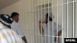 Muhammadruzi Burhonov appears behind bars in a district court.