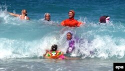 Burkini bilen suwa düşýän zenanlar.