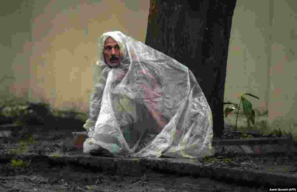 A Pakistani laborer looks on under plastic sheeting to keep dry from the rain in Islamabad. (AFP/Aamir Qureshi)