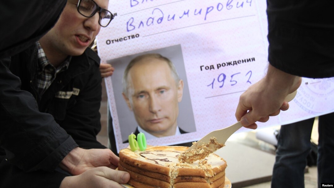 Орусия -- Оппозиция активисттери президент Путиндин сүрөтү чапталган пенсионердик карточканын алдында торт кесип жатат. Москва, 7-октябрь, 2012.