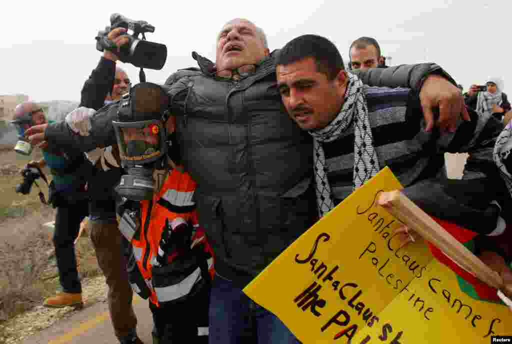 A Palestinian cameraman is evacuated after inhaling tear gas fired by Israeli troops during clashes at a protest in the West Bank city of Bethlehem on December 23. (Mussa Qawasma/Reuters)