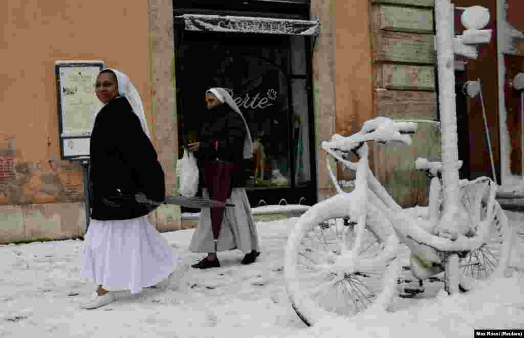 Nuns walk past a bike covered in snow during a heavy snowfall in Rome. (Reuters/Max Rossi)