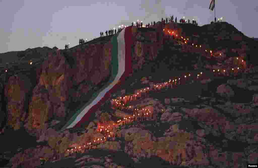 Iraqi Kurdish people carry torches up a mountain where a giant flag of Iraq&#39;s autonomous Kurdistan region is laid, as they celebrate Norouz Day, a festival marking their spring and new year, near Dahuk, on March 20. (Reuters/Azad Lashkari)