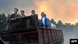 Volunteers ride on a trailer as they prepare to extinguish a fire at a forest near the village of Tokhushevo, some 50 kilometers outside Sarov.