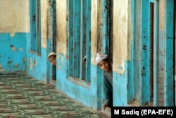 Afghan boys peek out from inside a madrasah in Kandahar.