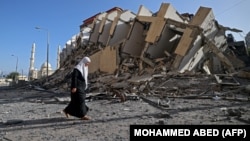 Palestinka prolazi pored uništene zgrade u gradu Gazi, fotografija iz 2021. godine