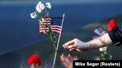 Një grua vendos lule dhe një flamur amerikan në memoralin për viktimat e 11 shtatorit në Nju Jork. Fotografi nga arkivi.
