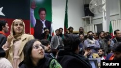 Volunteers for former Prime Minister Imran Khan's party, Pakistan Tehrik-e-Insaf (PTI), look on as they watch election results on TV screens in Islamabad on February 8.