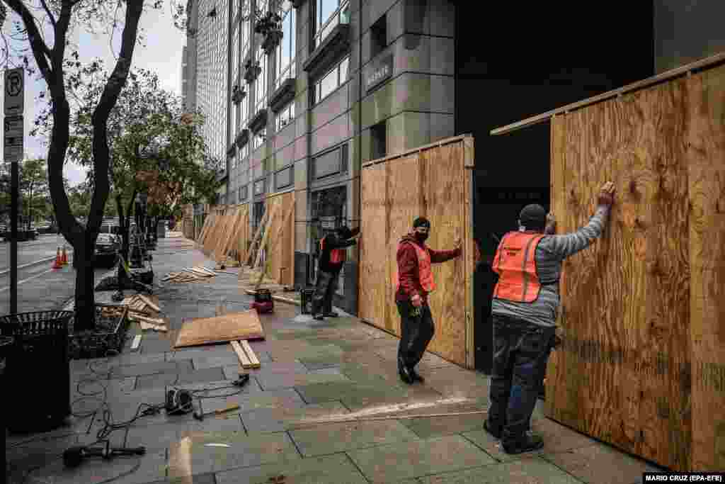 Работници поставуваат дрвени плочи со цел да обезбедат продавница во Вашингтон