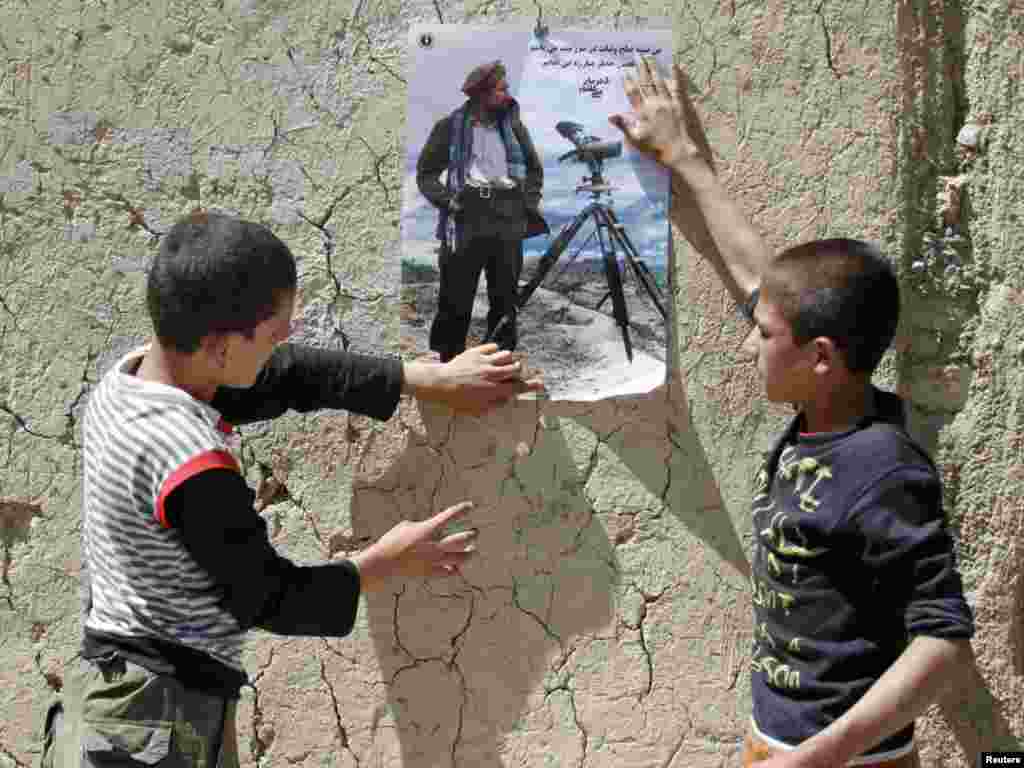 Afghan boys paste a poster of national hero Ahmad Shah Masud on a wall in the northern Panjshir Province on September 7. (Photo by Mohammad Ismail for Reuters)