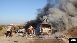 Волонтеры группы «Сирийская гражданская оборона», известной как «Белые каски», возле горящей машины в районе Сурана, Сирия. 