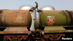 India -- A worker walks atop a tanker wagon to check the freight level at an oil terminal on the outskirts of Kolkata, November 27, 2013