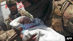 Припадник на авганистанските безбедносни сили носи бебе по нападот на болницата во Кабул. 