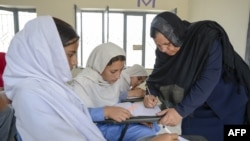 Aqeela Asifi (R) teaches Afghan refugee and Pakistani girls at her school in Kot Chandana refugee village in Mianwali.