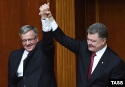Ukrainian President Petro Poroshenko (right) lifts high the hand of his Polish counterpart Bronislaw Komorowski during a session of the parliament in Kyiv on April 9.