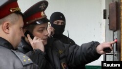 Russian Interior Ministry officers enter the building where opposition leader Sergei Udaltsov lives during a search operation in Moscow on October 17.