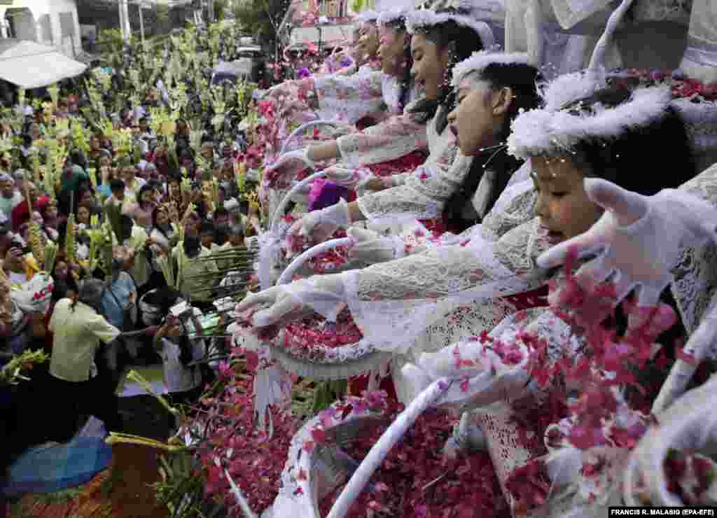 Filipino children shower flower petals onto Catholic devotees holding decorative palm fronds during a procession to mark Palm Sunday in Las Pinas City, south of Manila, on April 14. (epa-EFE/Francis R. Malasig)