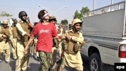 Pakistani soldiers detain a suspect at the site of a car-bomb blast in Peshawar on October 23.