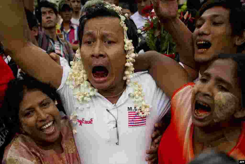 A newly-released inmate is reunited with family members after walking out of Burma's Insein Prison following a prisoner release in Yangon on July 30. (AFP/Ye Aung Thu)