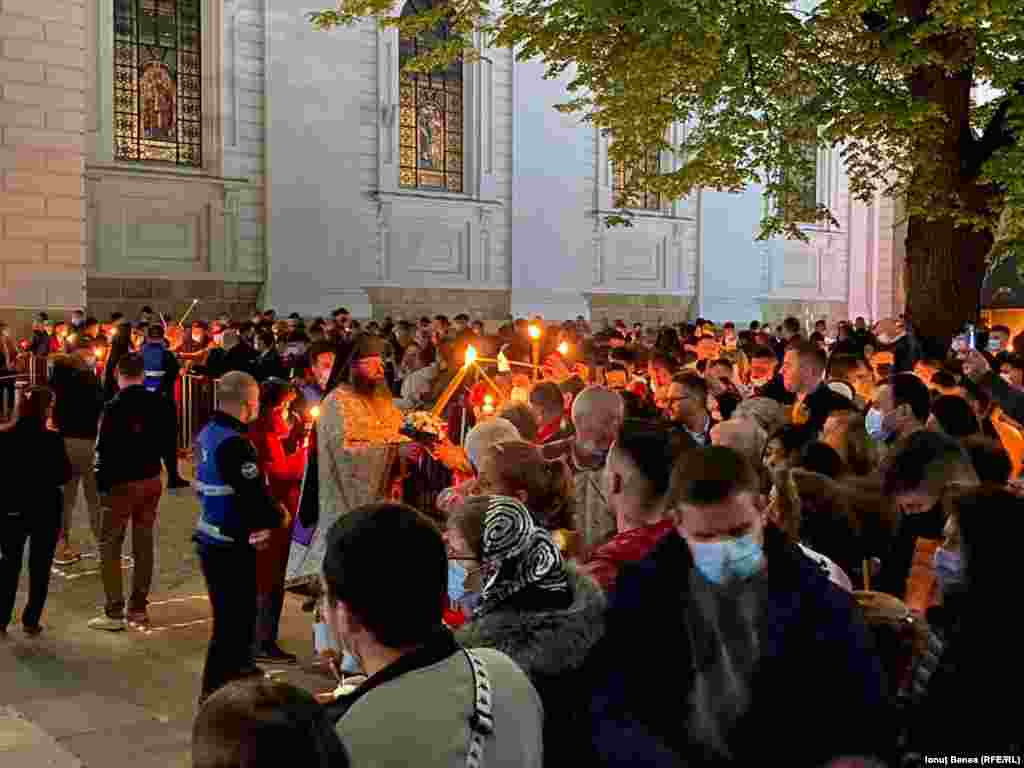 Un preot împarte credincioșilor lumină cu ocazia Paștelui ortodox, în curtea Catedralei Mitropolitane din Iași, România.