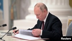 Ruski predsednik Vladimir Putin potpisuje dekret kojim se dve otcepljene regije koje podržava Rusija u istočnoj Ukrajini priznaju kao nezavisne države, tokom ceremonije u Moskvi, 21. februara 2022.