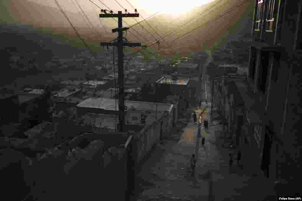 Afghans walk in an alleyway as the sun sets in Kabul.