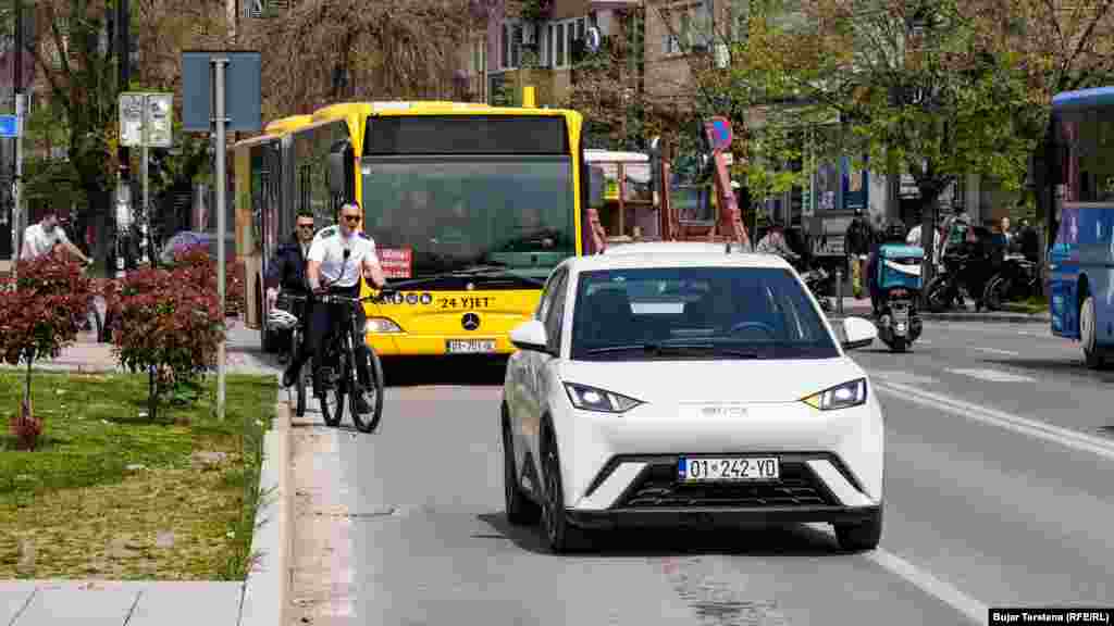Një veturë elektrike shihet në rrugët e Prishtinës, teksa pas tij është një autobus i një linje private që operon në Prishtinë. Për të nxitur qytetarët që të përdorin transportin publik, në Prishtinë, autoritetet lokale kanë bërë integrimin e biletave të autobusëve, duke u mundësuar qytetarëve që me një biletë (bileta ditore kushton 0.80 centë) të mund të udhëtojnë me të gjitha linjat brenda një dite.