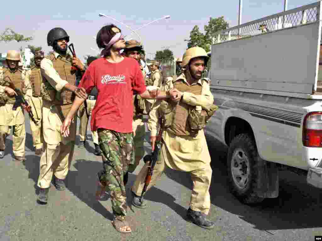 Pakistan -- Soldiers detain a suspect at the site of a car bomb blast in Peshawar, 23Oct2009 - Caption: epa01907640 Paramilitary soldiers detain a suspect at the site of a car bomb blast in Peshawar, the capital of North-West Frontier Province (NWFP) in Pakistan on 23 October 2009. A remote-controlled bomb planted in a car, exploded on 23 October 2009 in Peshawar and injured nine people. In another attack, a suicide bomber killed seven people and wounded more than a dozen outside the Pakistan Air Force's main production and maintenance facility in the eastern province of Punjab