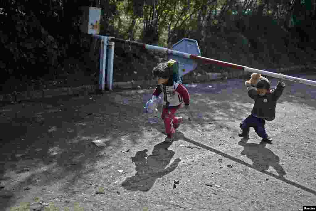 Children holding stuffed toys pass under the Serbian border barrier as migrants cross into Croatia, near the village of Berkasovo. (Reuters/Dado Ruvic)