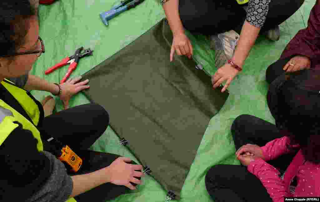 In the makeshift refugee camp at Moria, material salvaged from the boats is laid out and precut on a mat. Lesbos may be the end of the road for some migrants in the camp, but two young Dutch women have come up with an idea to recycle the wreckage of this crisis and inspire young migrants.