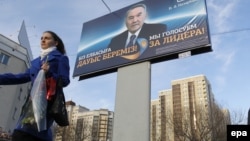 Нұрсұлтан Назарбаевтың сайлау алды билборды маңынан өтіп бара жатқан әйел. Астана, 31 наурыз 2011 жыл. (Көрнекі сурет)