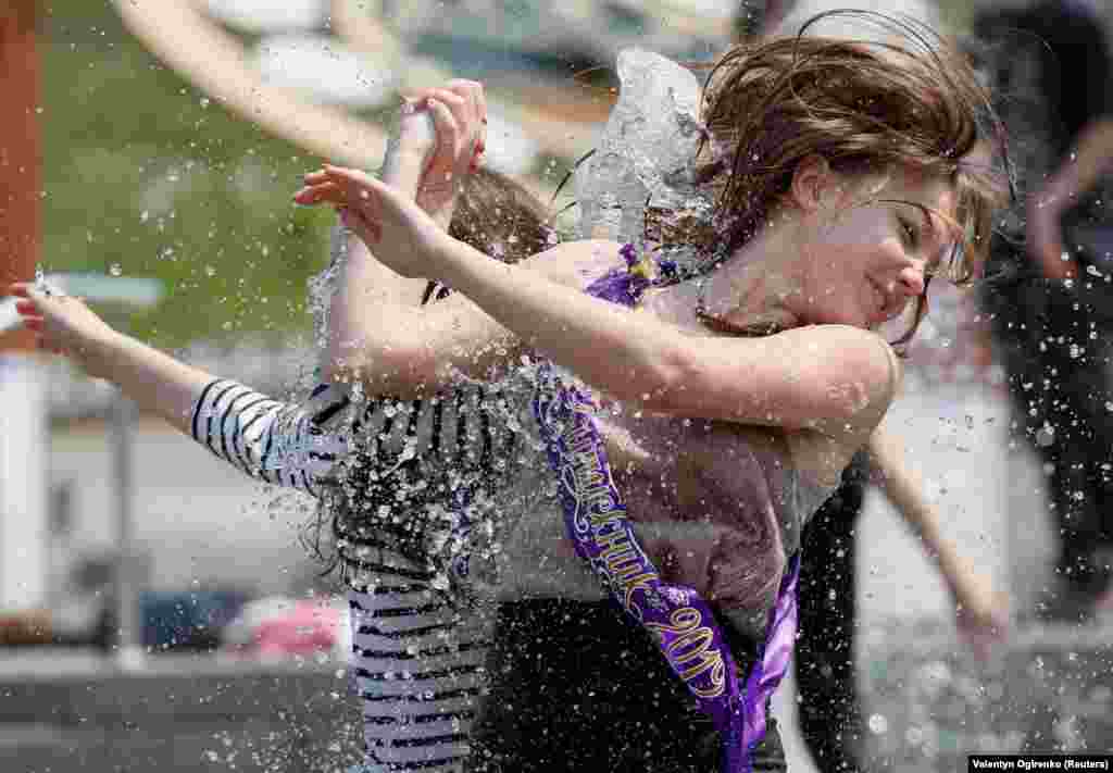 Secondary-school graduates play in a fountain as they celebrate the last day of school, traditionally called the "last bell," in central Kyiv on May 31. (Reuters/Valentyn Ogirenko)