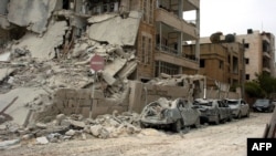 A building and vehicles that were damaged following blasts in the city of Idlib on April 30.