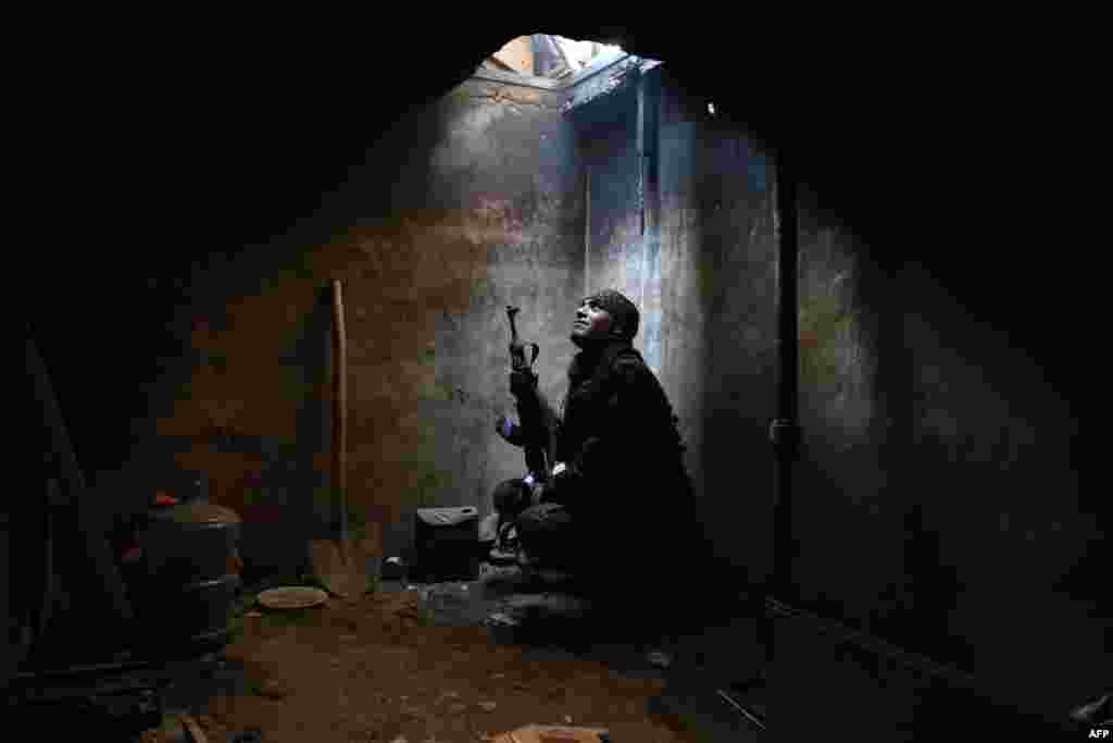 A rebel fighter, reportedly belonging to the Faylaq al-Rahman brigade, looks up from his hiding spot in the rebel-controlled area of Arbeen, on the outskirts of the Syrian capital, Damascus. (AFP/Amer Almohibany)