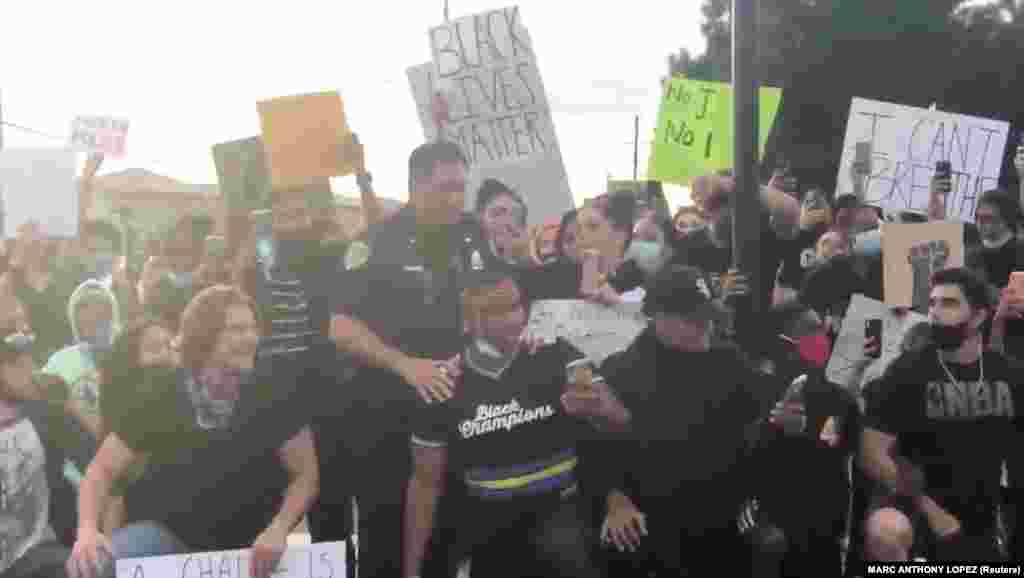 A Brentwood police officer joins with protesters demonstrating against the death of George Floyd in Minneapolis, in Brentwood, California, U.S. in this still picture obtained from May 31, 2020 social media video. 