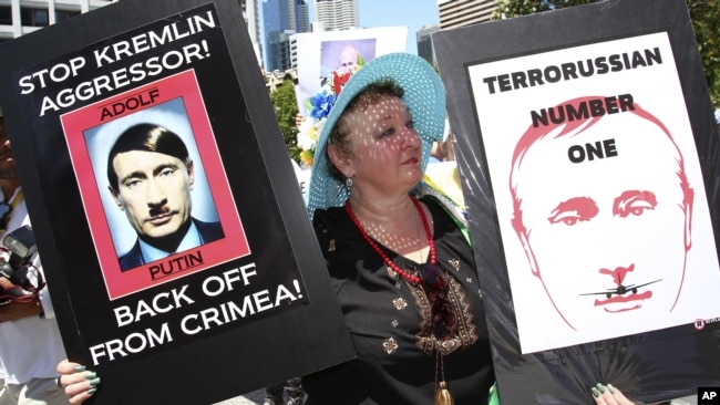 An anti-Russian protester holds placards at a rally during the G20 in Brisbane, Australia, in November 2014.