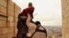 Islamic State militants prepare to throw a man from a high rooftop in Mosul as punishment for being gay.